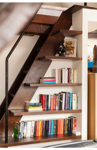 Una estantería llena de libros debajo de una escalera. en B&B Art and Sleep, en Amberes