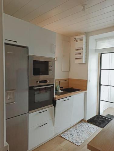 d'une cuisine équipée d'appareils en acier inoxydable et d'une fenêtre. dans l'établissement Maison chaleureuse et familiale idealement situee, à Groix