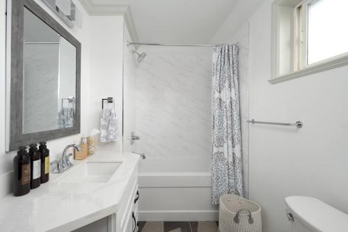 a white bathroom with a sink and a shower at Boutique Beach Apartment in Vancouver