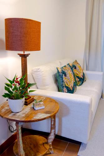 a living room with a white couch and a table with a lamp at Zur Suítes in Campos do Jordão