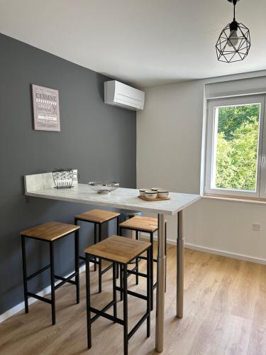une cuisine avec une table et des tabourets ainsi qu'une fenêtre dans l'établissement Horizons du Haut, à Niederbronn-les-Bains