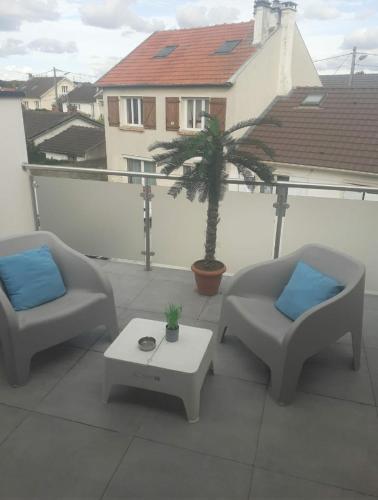 2 chaises et une table sur un balcon avec un palmier dans l'établissement Love Room Séduction, à Tremblay-en-France