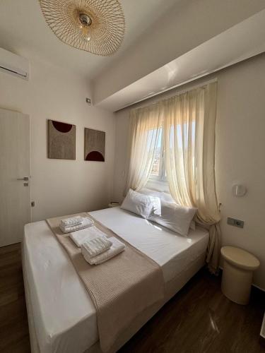 a bedroom with a large white bed with a window at Cerro Fine Living in Ermoupoli