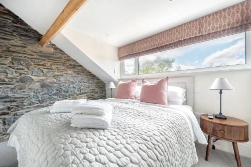 a bedroom with a large bed with a stone wall at 4 Beckside Cottage in Windermere