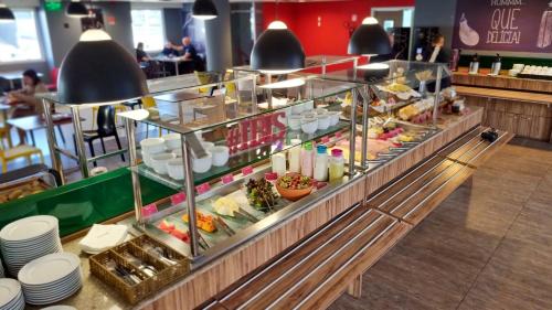 a buffet line in a restaurant with plates and food at ibis Rio de Janeiro Parque Olimpico in Rio de Janeiro