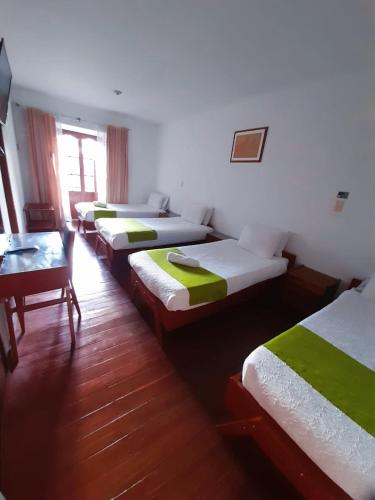 a row of beds in a room with a table at Hotel El Cid Plaza Premium in Tunja