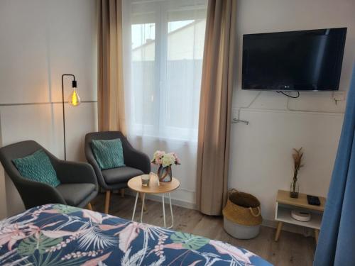 Cette chambre comprend un lit, deux chaises et une télévision. dans l'établissement Calme - Wifi - Netflix - Stationnement gratuit, à Lens