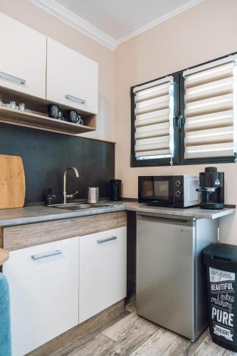 a kitchen with white cabinets and a sink and a microwave at Villa Apartman in Makó
