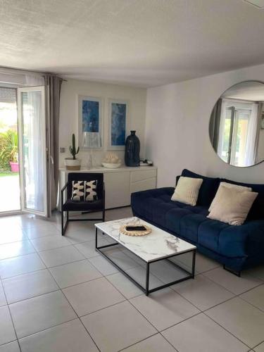 un salon avec un canapé bleu et une table dans l'établissement Bel appartement T3 avec jardin Malibu Village, à Canet