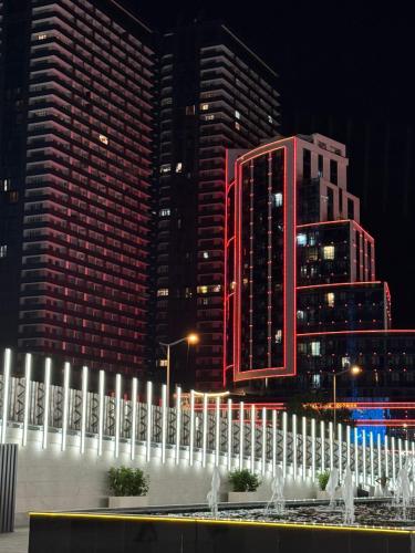 a fountain in front of some tall buildings at night at Moonlight Apart-Hotel Batumi in Batumi