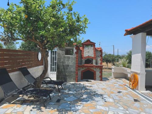 a patio with a tree and a brick oven at Nereid Bungalow in Phanaes