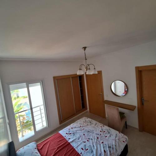 a bedroom with a bed and a window and a mirror at Superbe appartement, vue piscine in Saidia 