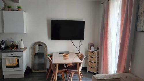 un salon avec une table et une télévision au mur dans l'établissement Bel appartement 10 min de Paris, à Houilles