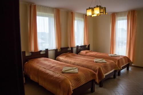 three beds in a room with orange curtains and windows at Greta in Druskininkai