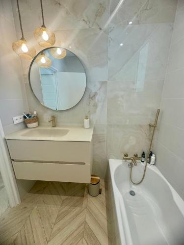 une salle de bain avec une baignoire, un lavabo et un miroir dans l'établissement le somptueux, à Antibes