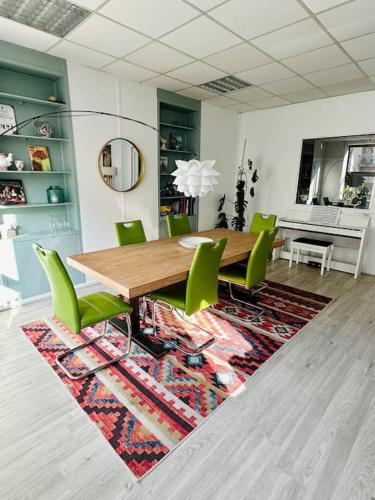 une salle à manger avec une table en bois et des chaises vertes dans l'établissement Cosy duplex aux portes de Paris, à Issy-les-Moulineaux