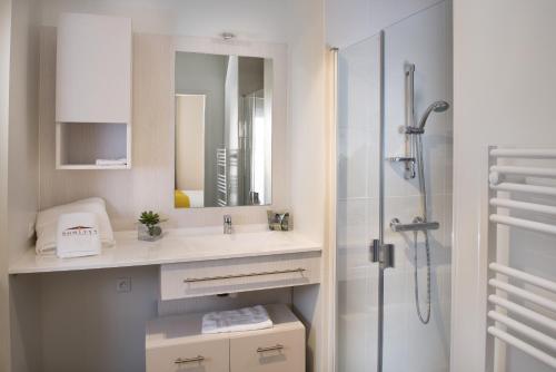 baño blanco con ducha y lavamanos en Domitys Les Dunes D'argent, en Saint-Cyprien