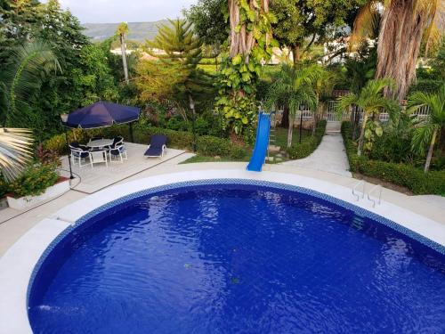 a large blue swimming pool with a table and umbrella at Casa Pinilla- Perfecta para Paseos in Ricaurte