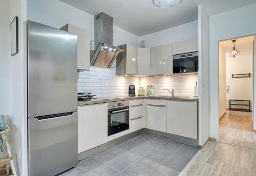 une cuisine avec des armoires blanches et un réfrigérateur en acier inoxydable dans l'établissement Bella Notte - 10 min from DisneyLand, Free Parking, Self Check-in, 7 pers, à Montévrain