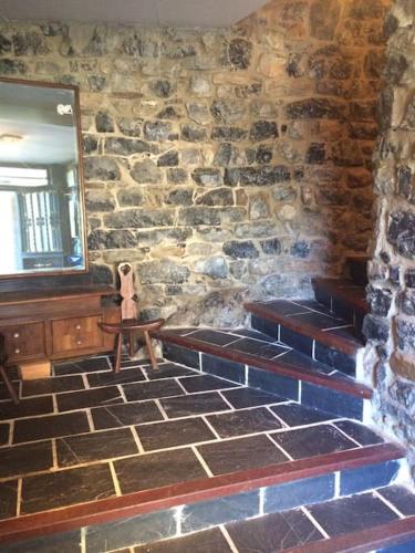 a stone wall with stairs in a room with a mirror at La casa de Juan el Cantero in Puebla de Lillo