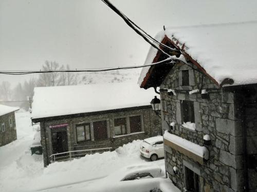 a house covered in snow with cars parked in front of it at La casa de Juan el Cantero in Puebla de Lillo