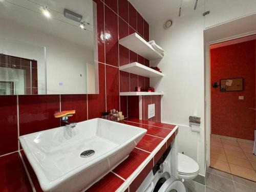 La salle de bains est pourvue d'un lavabo blanc et d'un mur rouge. dans l'établissement Stylish 1BR with Peaceful Garden in 18th District, à Paris