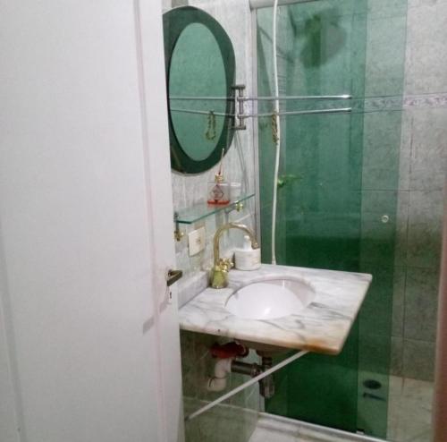 a bathroom with a sink and a shower with a mirror at Quarto Privativo - Pitangueiras - 50mts da Praia in Guarujá