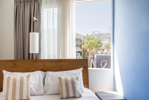 a bedroom with a bed with white pillows and a window at Theo Apartment Rethymno in Rethymno