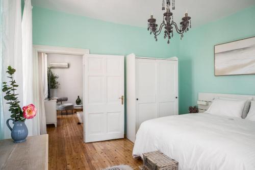 a bedroom with a white bed and a chandelier at Infinite Residences - Central Location, Tradition and Comfort in Corfu Town