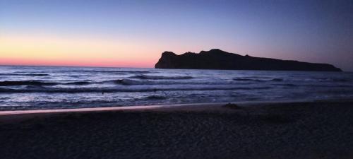 a beach with a mountain in the ocean at sunset at Blue Lotus Studio in Agia Marina Nea Kydonias
