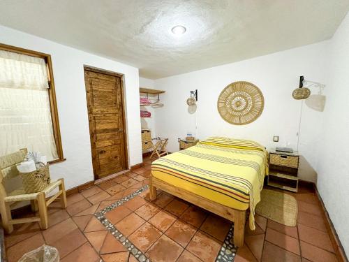 a bedroom with a bed and a chair and a window at Posada El Palomar in Pátzcuaro