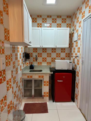 a small kitchen with white cabinets and a red refrigerator at Viva a bela Copacabana! in Rio de Janeiro