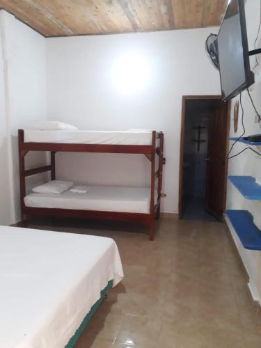a room with two bunk beds and a tv at Hotel Zona Libre Capurganá - Cerca a la playa y el muelle in Acanti