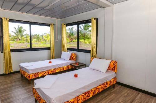 a room with two beds and two windows at Shalini Garden Hotel & Apartments in Singatoka