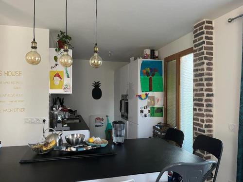 une cuisine avec un comptoir noir dans une pièce dans l'établissement Duplex-pied du village JO paris, à LʼÎle-Saint-Denis