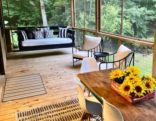 a porch with a table and chairs and a couch at Close to Lake Blue Ridge, Hot Tub, Swing Beds in Morganton