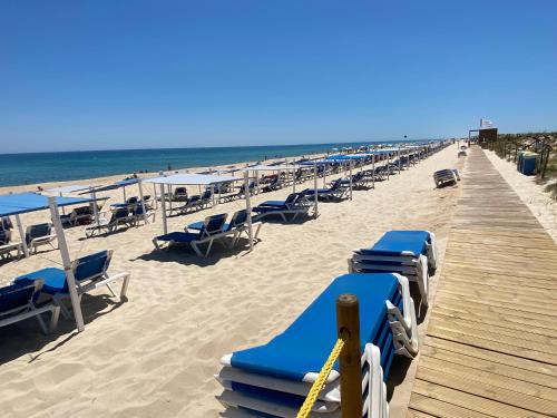 a row of beach chairs and umbrellas on a beach at Studio Pedras del Rei - Casa Verde in Tavira