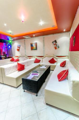 a living room with white couches and red pillows at Hotel Cosmos in Asenovgrad