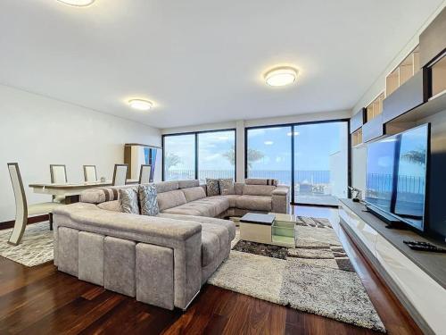 a living room with a large couch and a television at Villa Ribeiro Real 12 A in Câmara de Lobos