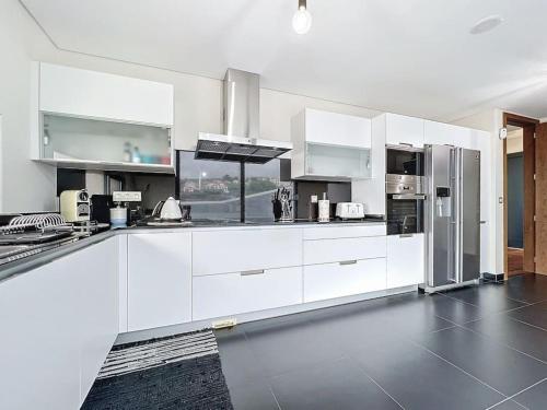 a white kitchen with white cabinets and appliances at Villa Ribeiro Real 12 A in Câmara de Lobos