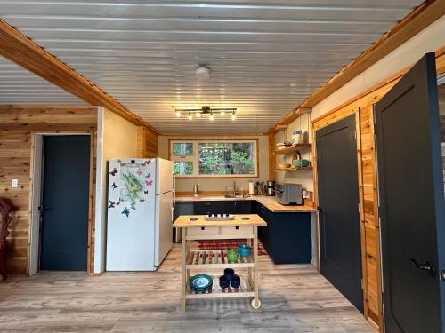 a kitchen with a refrigerator and a table in it at Thetis Island Get Away Cottage in North Galiano