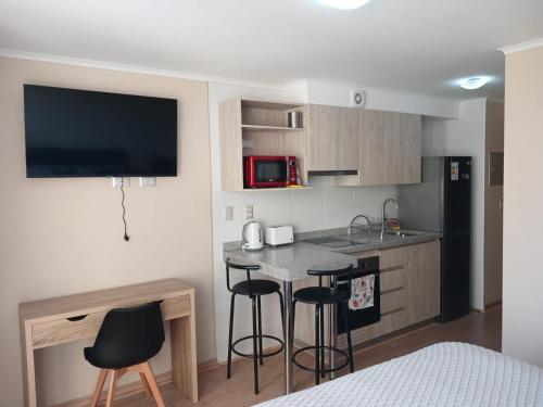 une petite cuisine avec une table et deux tabourets de bar dans l'établissement Departamento Osorno centro, à Osorno