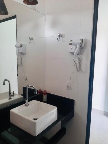 a bathroom with a white sink and a mirror at Pousada Lobo Guará in São João Batista do Glória