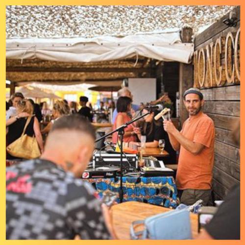 Un homme debout devant une foule de gens dans l'établissement Havre de paix, proche de la mer, à Sérignan