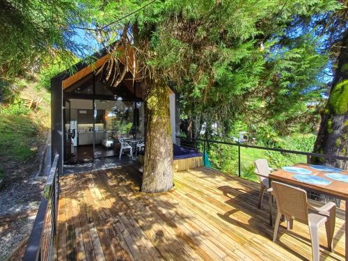 una terraza con un árbol, una mesa y sillas en Tree House, Cabaña privada con Jacuzzi, en Guatapé