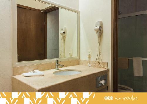 a bathroom with a sink with a mirror and a phone at Hotel Tres Soles in Ciudad Madero