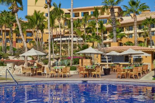 a hotel with tables and chairs next to a swimming pool at Grand Fiesta Americana Los Cabos All Inclusive Golf & Spa in Cabo San Lucas