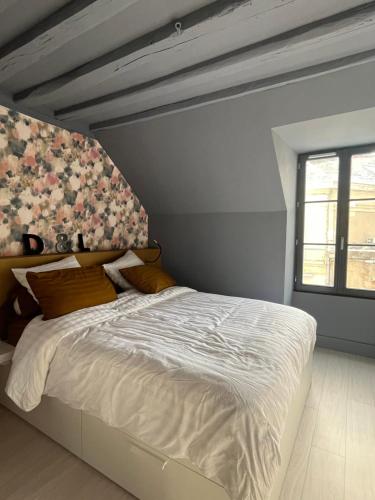 a bedroom with a white bed with a floral wall at Petite maison centre ville châteaudun in Châteaudun