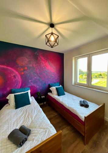 two beds in a room with a painting on the wall at Butter Chill House - Dom na Kaszubach in Masłowo