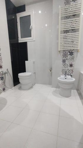 a white bathroom with a toilet and a sink at Guest house DAR Al YASMINA in Tunis